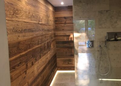 Linke Ansicht eines Badezimmers mit sonnenverbrannter Altholz-Wandverkleidung und grauen Bodenfliesen.