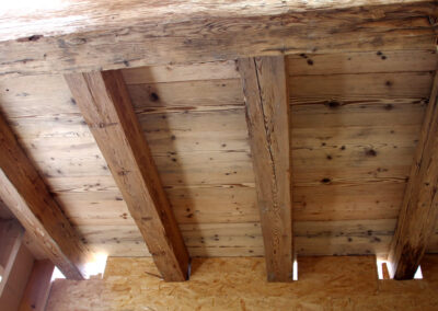 Innenansicht einer Deckenkonstruktion mit massiven, handgehackten Altholz-Sparren für ein rustikales und exklusives Raumambiente.