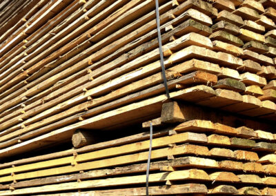 Großer Stapel unbesäumter Altholzbretter, roh, mit handgehackter Oberfläche im Lager vom Altholzcenter Buchegger.