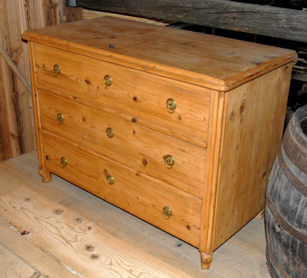 Ansicht einer massiven Kommode aus Altholz mit drei Schubladen, die die warme Holzfarbe und die handwerkliche Verarbeitung zeigt.