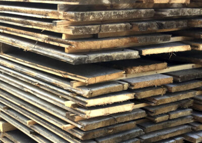 Ein großer Stapel Altholz-Bodenbretter im Lager, bereit für die Weiterverarbeitung zu hochwertigen Bodenbrettern und massiven Dielen.