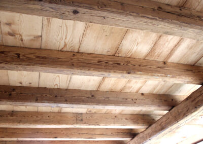 Seitenansicht einer Deckenkonstruktion mit massiven handgehackten Altholz-Sparren, die die plastische Oberflächenstruktur verdeutlicht.