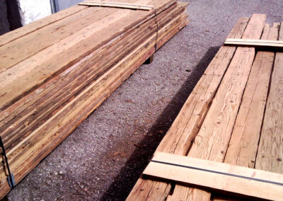 Zwei fachmännisch sortierte Stapel handgehackter und gebürsteter Altholzbretter, bereit für den Versand an den Kunden.