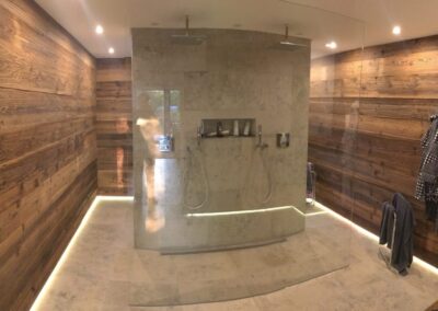 Zentrale Ansicht eines modern gestalteten Badezimmers mit Altholz-Elementen und anthrazitfarbenen Steinoptik-Fliesen.