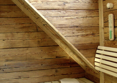 Detailaufnahme im Saunainnenraum: Altholz-Rückwand und Seitenwand mit präziser Anpassung an die Dachschräge.