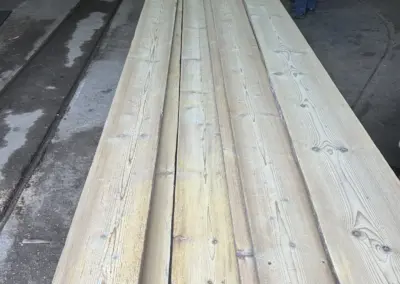 Ansicht eines Stapels besonders langer Altholz-Bodenbretter, ideal für durchgehende Verlegung in großen Sälen oder Lofts ohne viele Stöße.