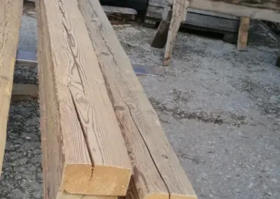 Blick von oben auf einen Stapel frisch aufbereiteter Altholz-Kanthölzer mit Fokus auf die saubere Oberfläche und die exakten Querschnitte.