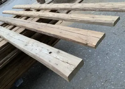 Vier querliegende Altholz-Sparren, 3-seitig sichtbar und handgehackt, präsentiert als Muster für Sichtdachstühle und Deckenbalken.