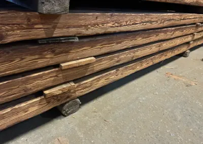 Nahaufnahme eines seitlich fotografierten Altholz-Sparrens, der die saubere, handgehackte Oberflächenstruktur nach der Aufbereitung zeigt.