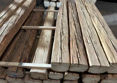 Detailansicht eines Stapels kurzer, handgehackter Altholz-Balken, die speziell für kleinere Projekte und den einfachen Transport sortiert sind.