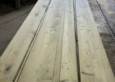 Frontale Ansicht eines Stapels breiter Altholz-Bodenbretter, die aus alten Stuben- und Tennenböden gewonnen wurden, mit Fokus auf die enorme Breite der Dielen.