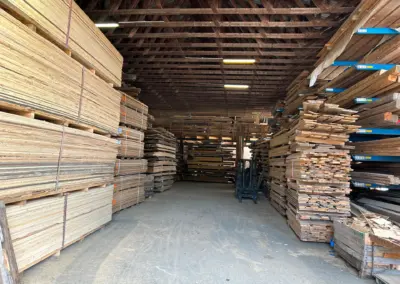 Gut sortierte, hohe Stapel von Altholzbrettern in der Lagerhalle, nach Längen und Breiten für den schnellen Zugriff organisiert.