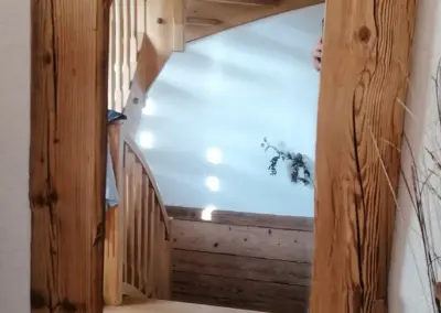 Ein rechteckiger Wandspiegel, dessen Rahmen aus massiven, handgehackten Altholzbrettern gefertigt ist, zeigt die rustikale Textur des Holzes.