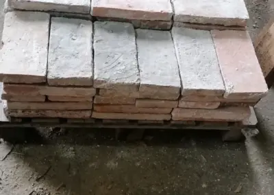 Perspektivische Ansicht eines Stapels alter roter Ziegelsteine, die die verschiedenen Schattierungen und die Kantenstruktur der Steine zeigt.