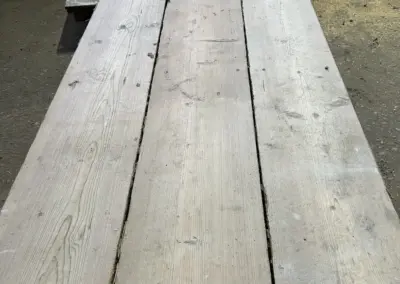 Detailaufnahme eines weiteren Stapels antiker Bodenbretter aus der Vogelperspektive, der die farblichen Nuancen und die urige Beschaffenheit des Altholzes betont.