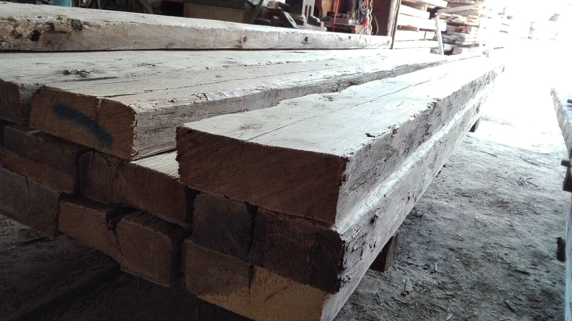 Detailaufnahme der Stirnseiten (Querschnitte) von aufbereiteten Altholz-Dübelbalken, die die Materialstärke zwischen 8 cm und 15 cm verdeutlicht.