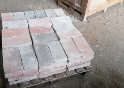 Ein sauber geschichteter Stapel antiker, roter Mauerziegel, die aus dem Rückbau historischer Gebäude geborgen wurden.