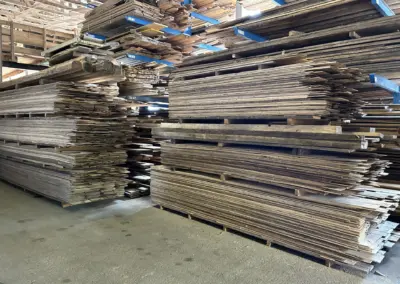 Innenaufnahme der Lagerhalle mit Fokus auf die breite Auswahl an Altholz-Schnittware in unterschiedlichen Formaten.